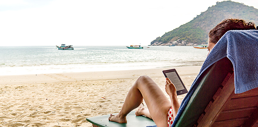 woman reading her kindle on a beach