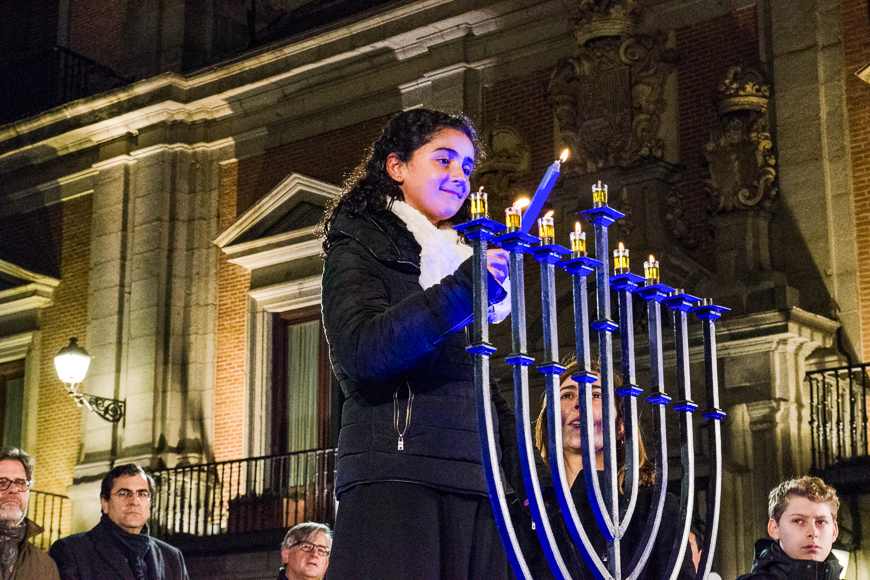 A young girl and the luna alfon (r), director of ibn gabirol estrella toledano school, lighting candles during hanukkah celebration