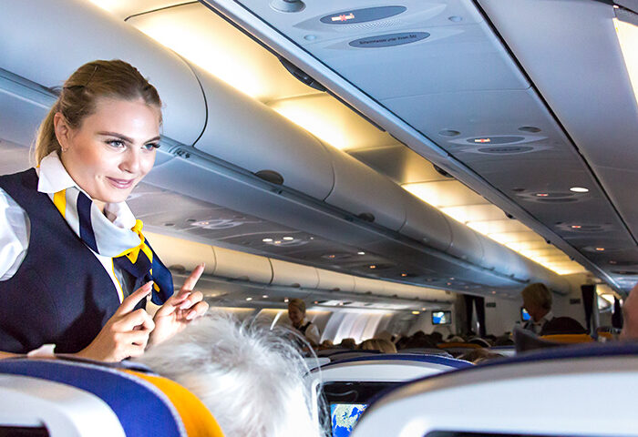 flight attendant speaking with passengers on flight plane