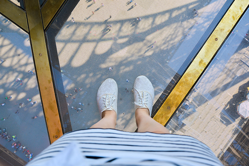 legs in white sneakers (shoes) and a skirt on glass floor eiffel tower.