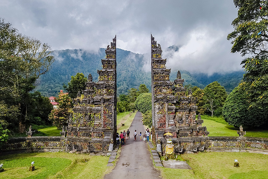 tourists walk through the gate of a hindu temple in bali