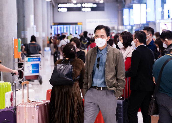 man in mask at crowded airport.