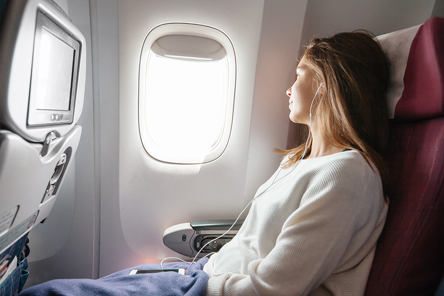 Teenage girl looking at plane window during flight. 