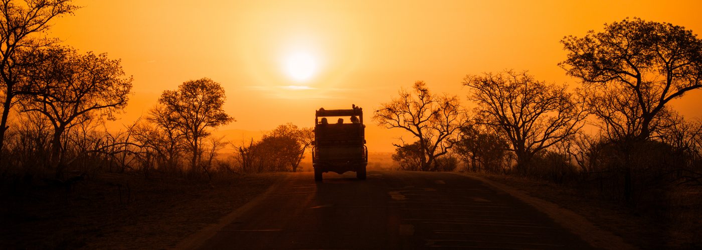 Silhouette of safari vehicle against sunset