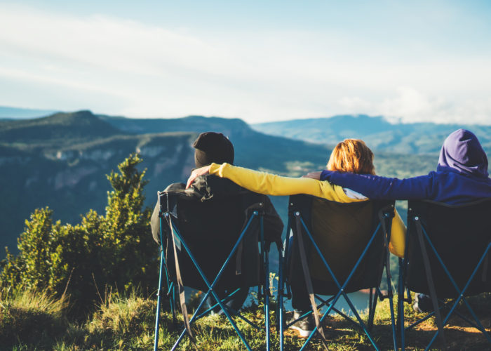Three friends sitting on camping chairs and looking at a view of the mountains