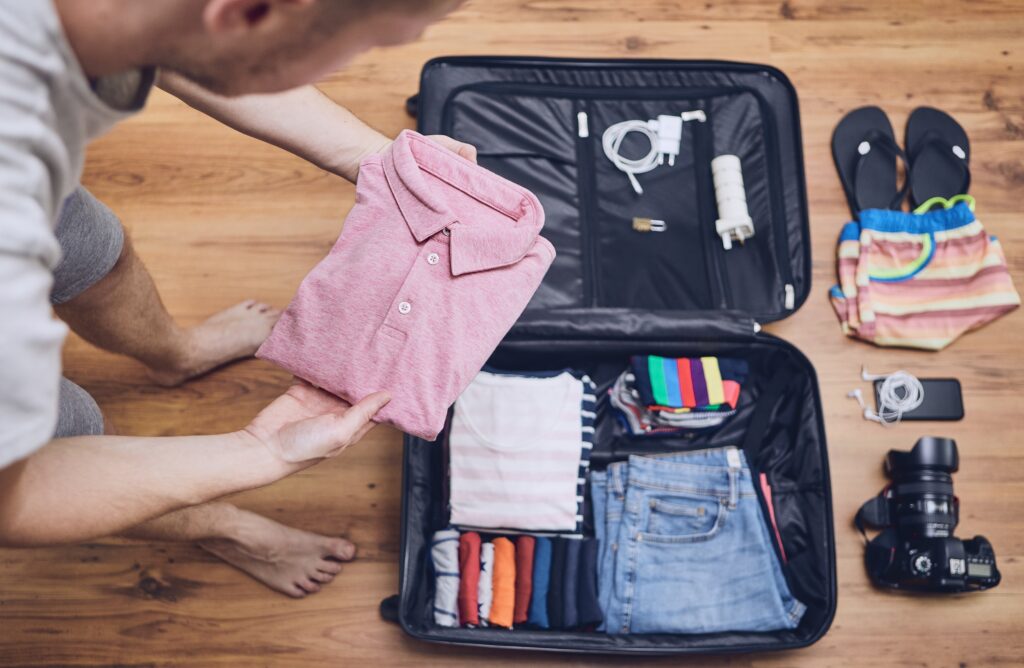 man packing suitcase for upcoming trip with gear spread out
