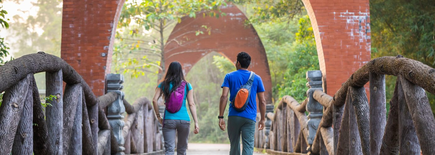two people walking along bridge touring with small backpacks on