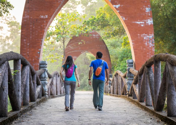 two people walking along bridge touring with small backpacks on