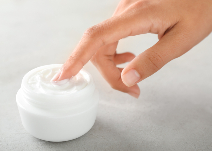 hand in small jar of lotion