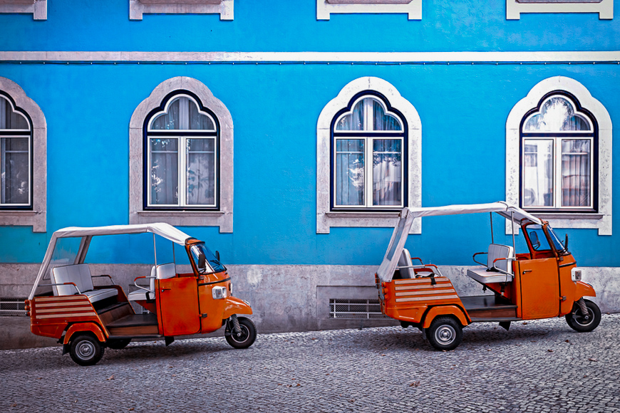 Tuk tuk vehicle in front of blue facade building in the Lisbon, Portugal. 