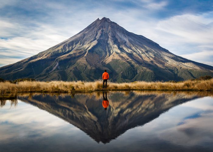 hiker looking at mountain with reflection of water
