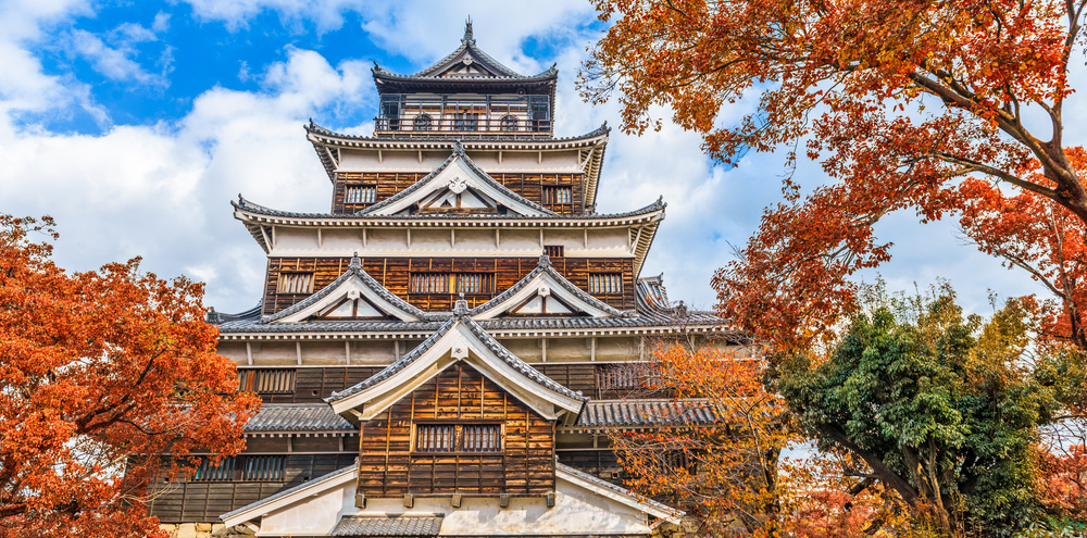 Tall japanese-style castle surrounded by trees showing autumn colors
