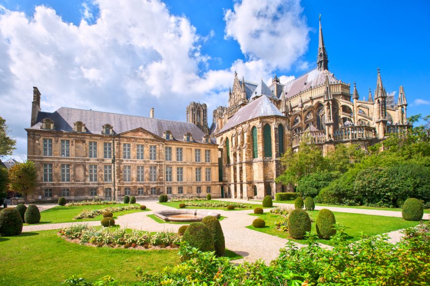 the back courtyard of the reims cathedral with lush green grass