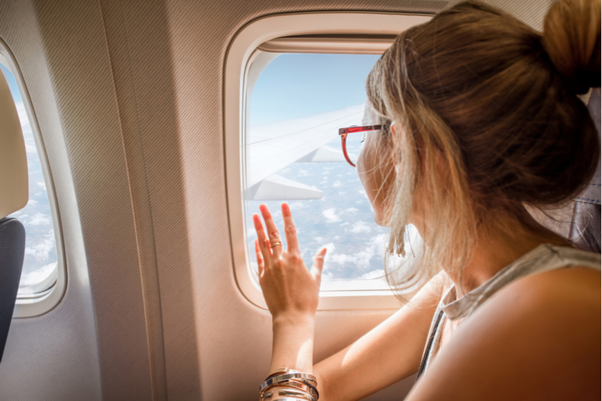 girl with glasses staring out plane window.