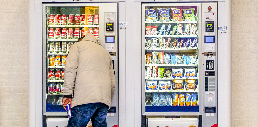 man purchasing soft drink vending machine