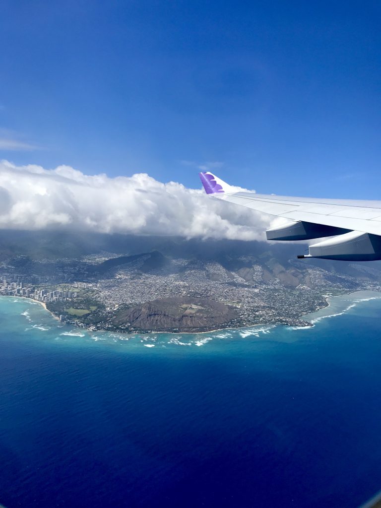 hawaiian airlines flying over diamond head crater and ocean.