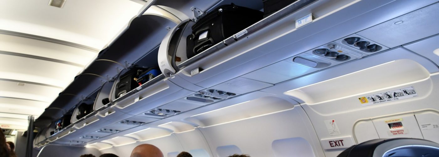 passengers on a plane with overhead bins open.