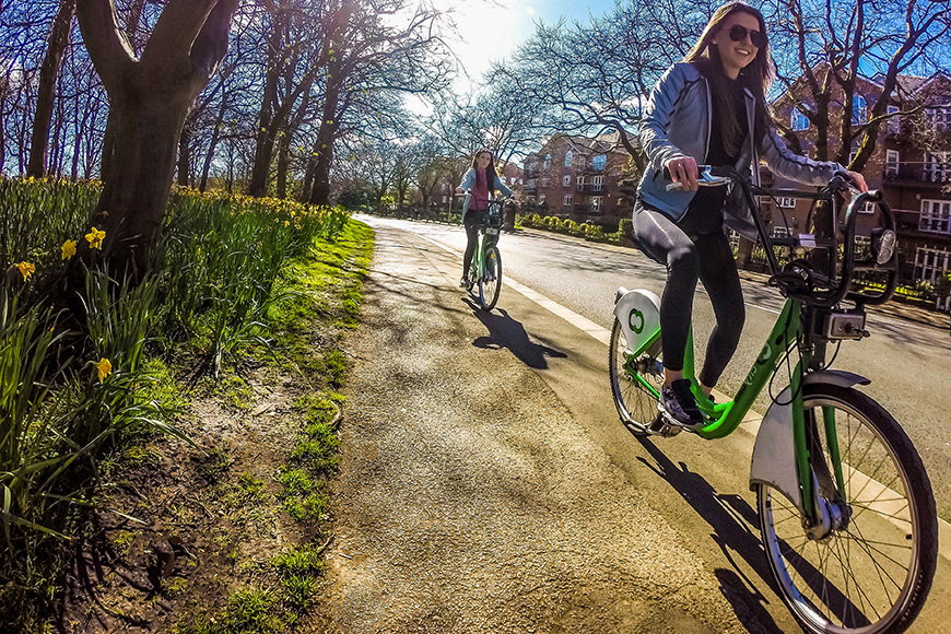 two women riding bicycles in city