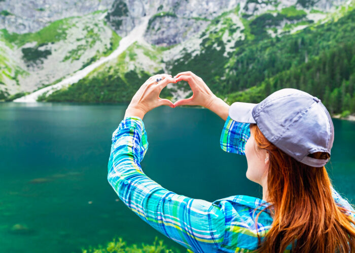 Girl make heart sign (shape of heart) on like, mountains background. In love with nature. Eye of the Sea lake (Morskie Oko). Tatra mountains. Poland.