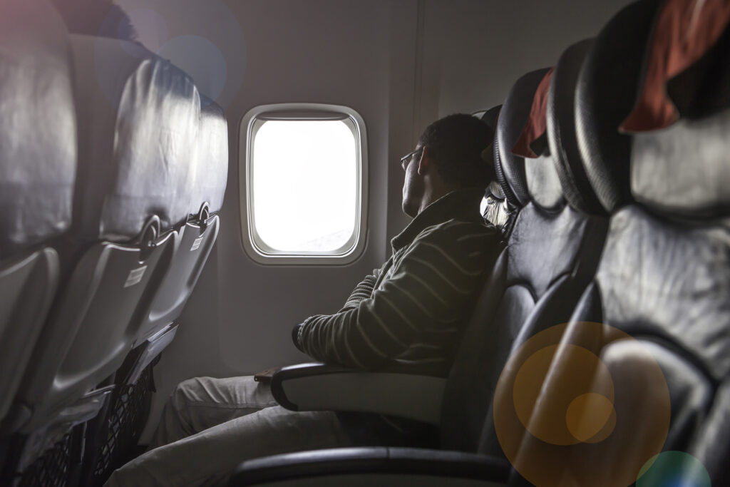 man sitting next to empty comfort seat on the plane.