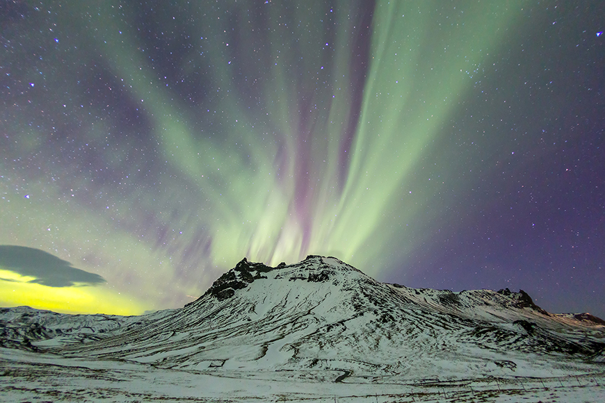 northern lights over mountain in iceland.