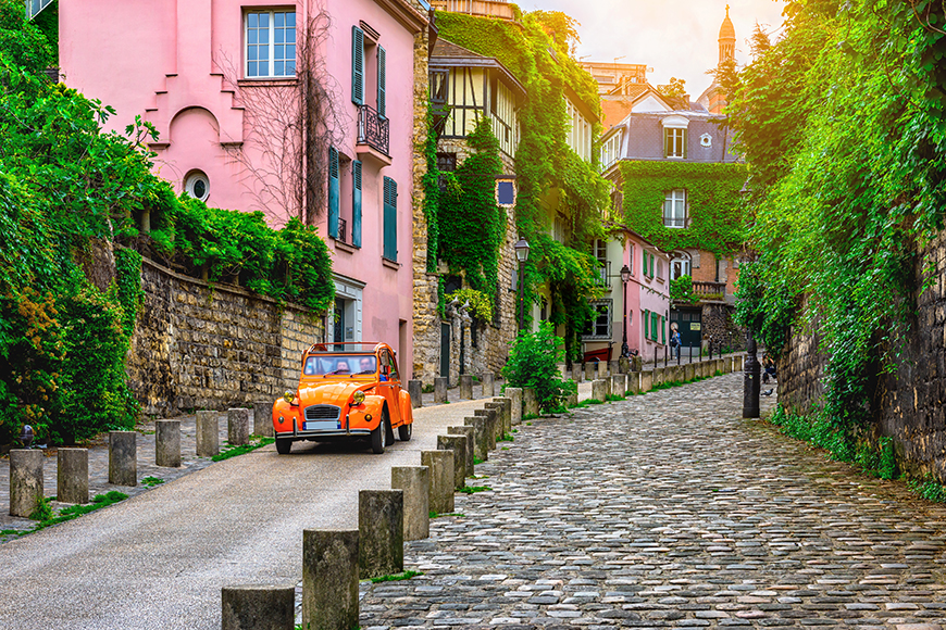 orange car on paris cobblestone street.