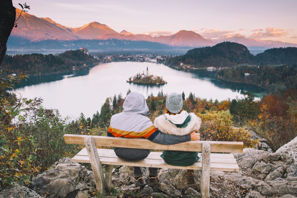 couple on bench in europe looking over mountain and lake