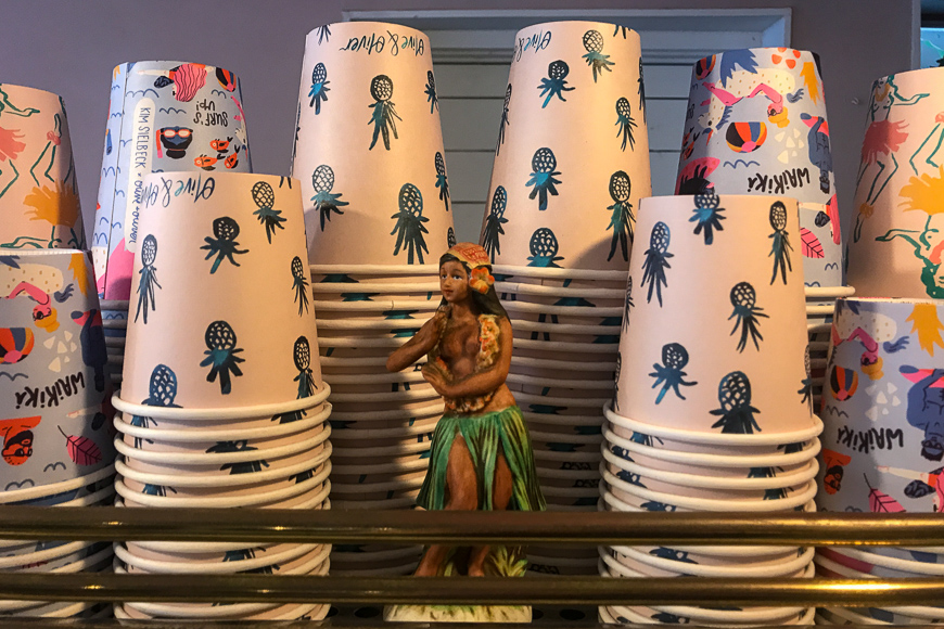 Hula girl statue next to cups 