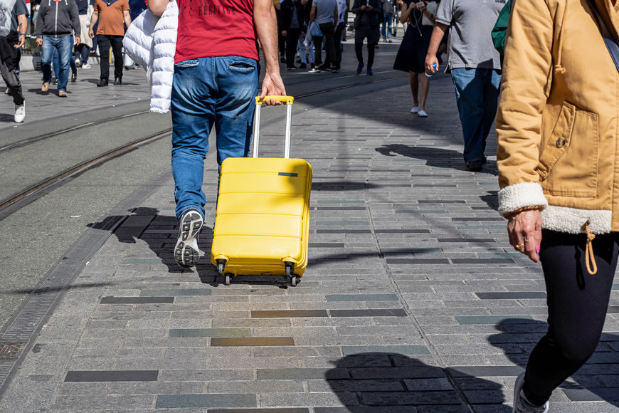 Man pulls yellow suitcase on the road