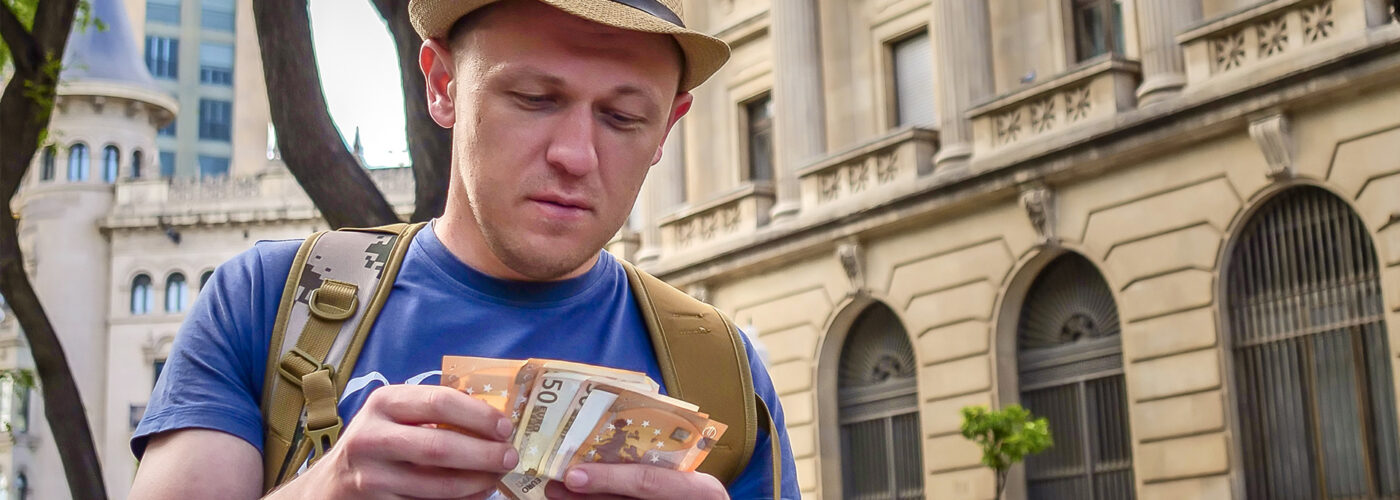 male tourist counts cash on the street of city