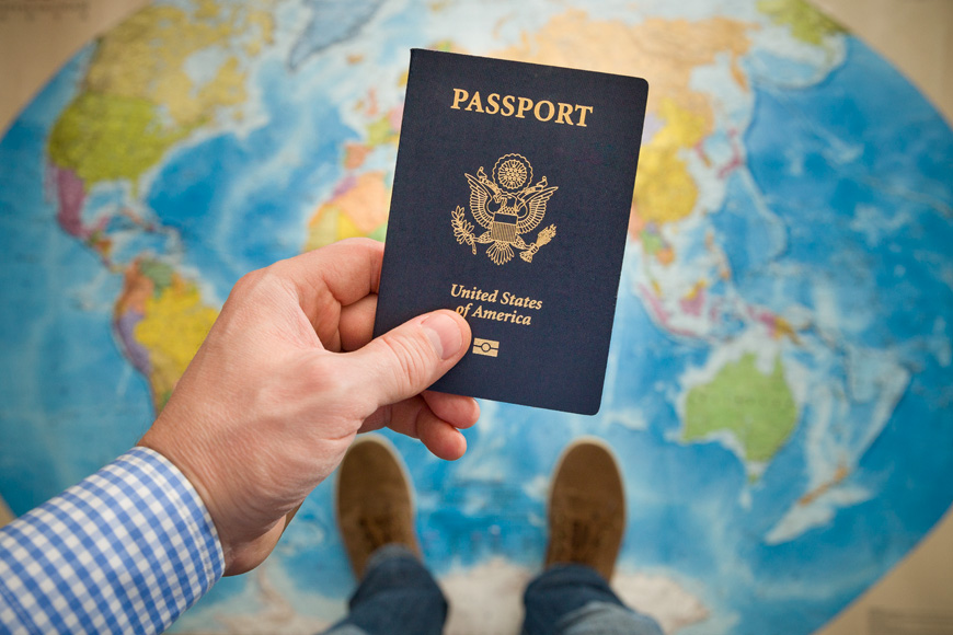 man holding U.S. passport over world map