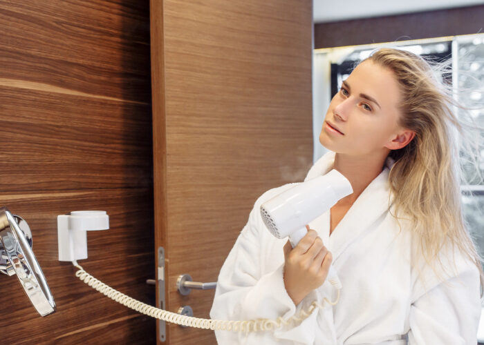 woman hotel room drying hair bathrobe bathroom