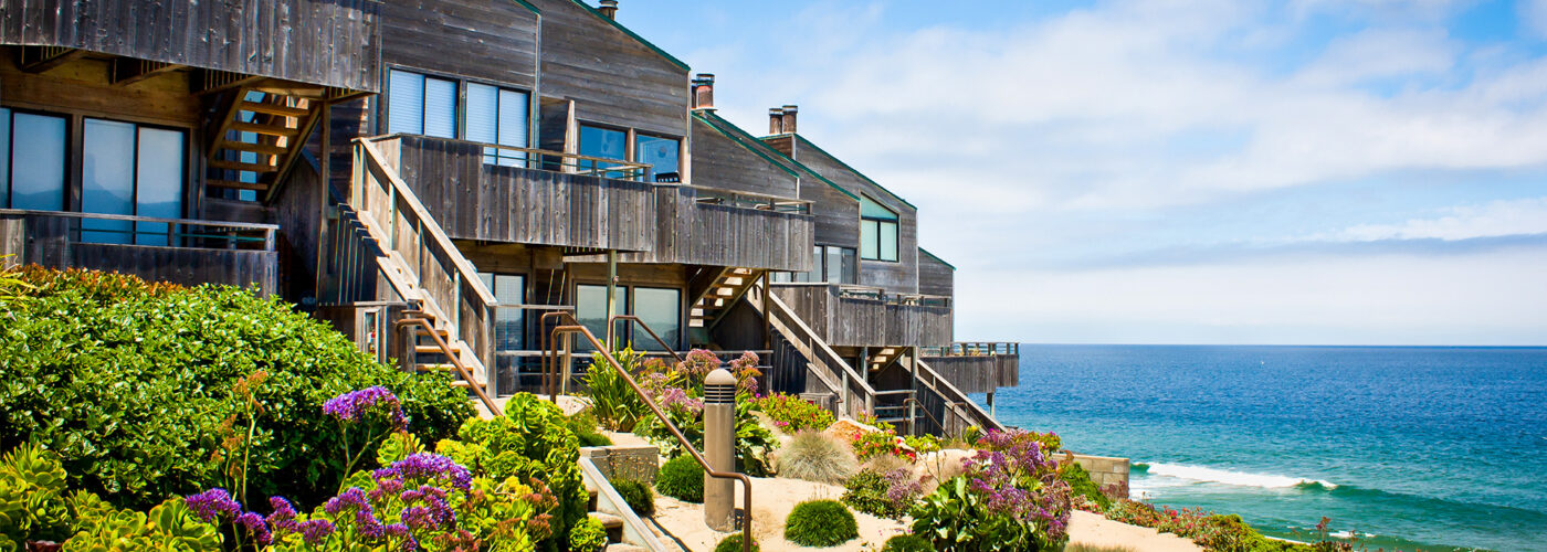 A row of oceanfront townhomes adjacent to a landscaped sand dune.
