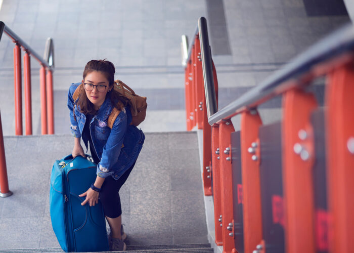 Young woman going up the stairs with her heavy suitcase