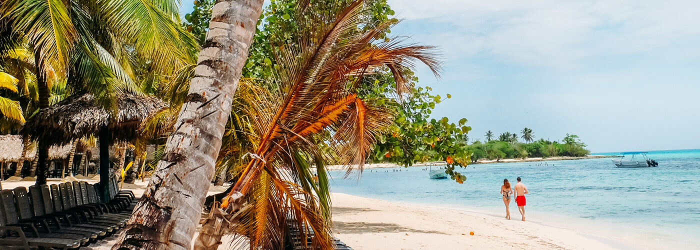 couple walking along beach palm trees