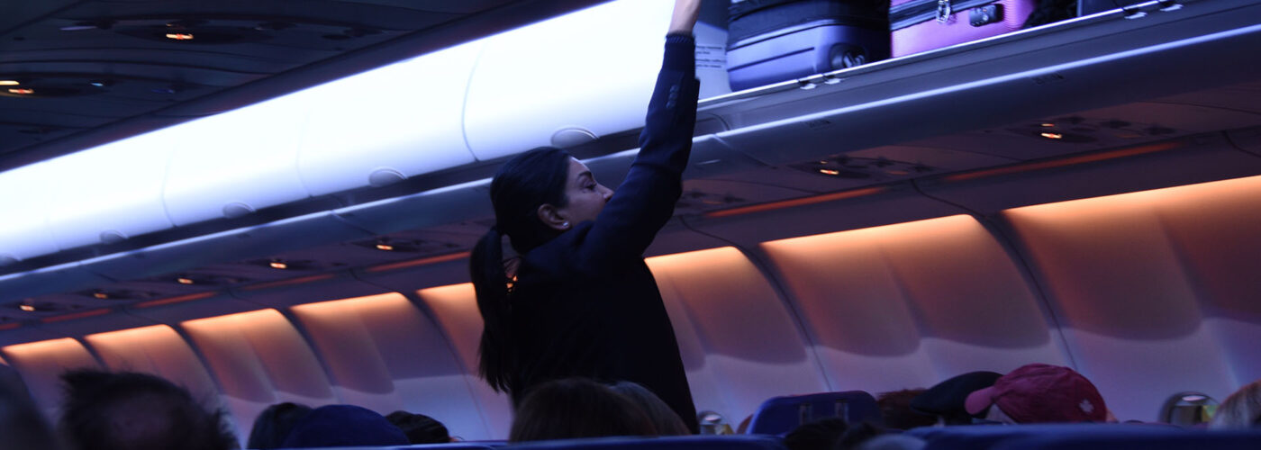 flight attendant closing overhead bin.
