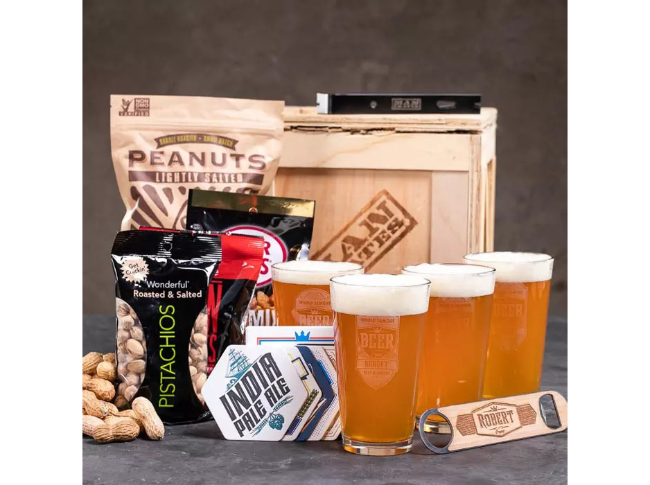 A Man Crate subscription box surrounded by glasses of beer, pistachios, peanuts, and a bottle opener