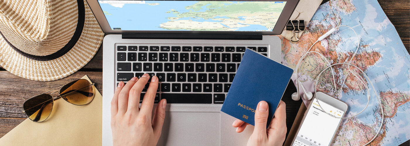 Female hand holding a passport over a laptop