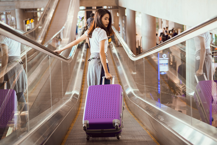 Asian woman traveler walking on escalator to airplane 