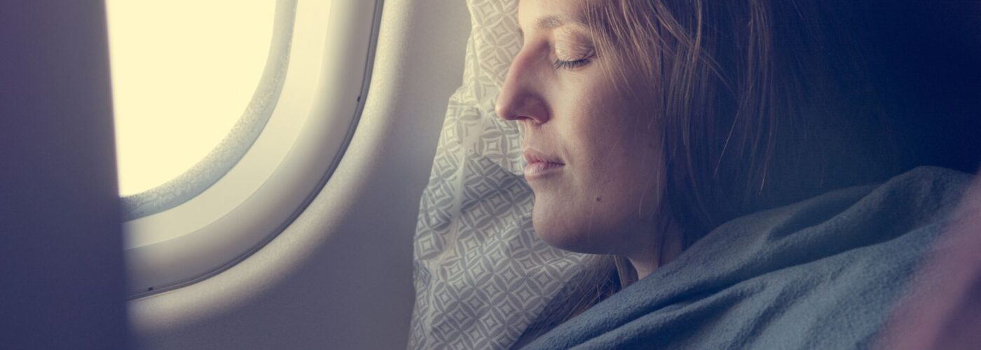 woman sleeping with blanket on plane