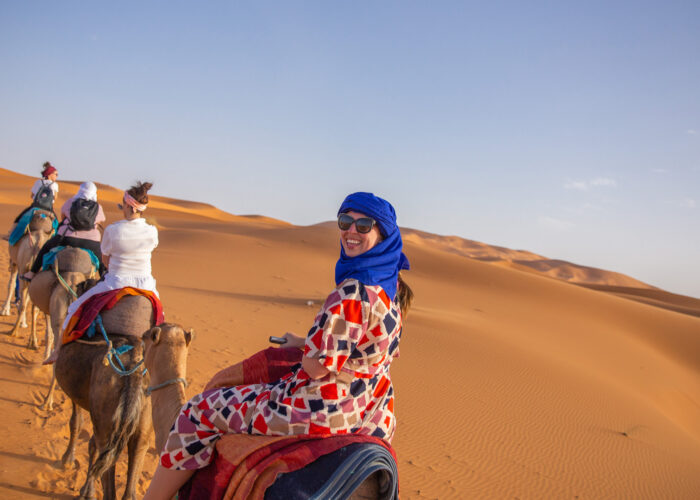 travelers ride on camels in shara desert Staff FOC trip to Morocco Uncovered (XMKC)