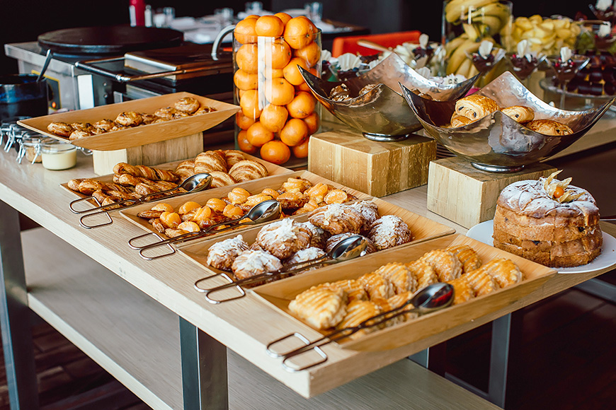 Assortment of fresh pastry and mandarin on table in buffet.