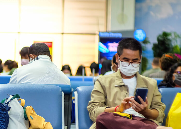 man wearing mask to protect against covid-19 coronavirus sits in airport gate