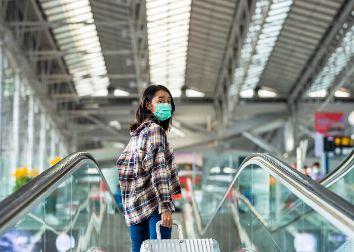 Asian woman tourist wearing face mask protection from coronavirus walking in the airport
