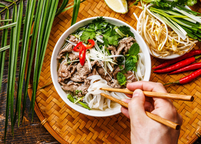 Pho Bo vietnamese Soup with beef and chopsticks in male hand