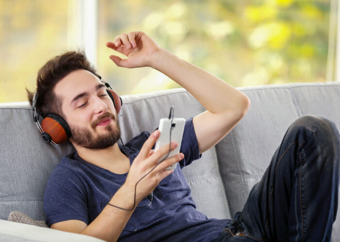 man listening to heapdphones on grey sofa