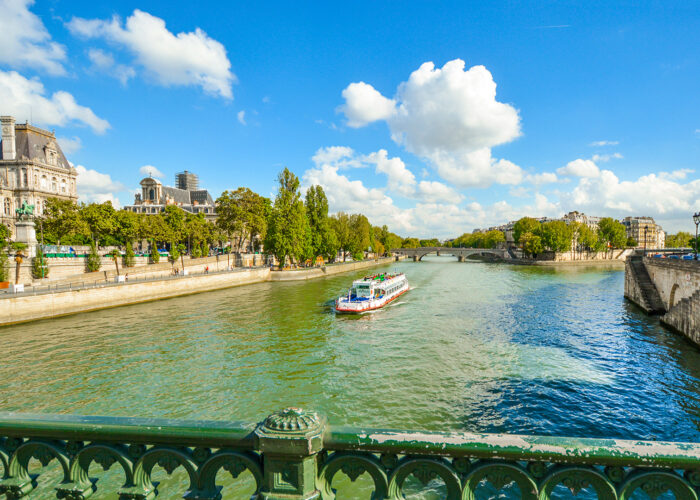 A cruise tourist boat floats down the Seine River near the Ile de la Cite in Paris, France