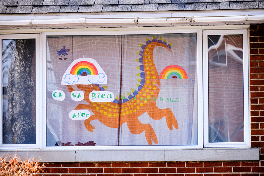 House window with rainbow drawings and slogan "Ca va bien Aller" as message of hope in Montreal part of "It's going to be OK" movement during CoVID19 epidemic 