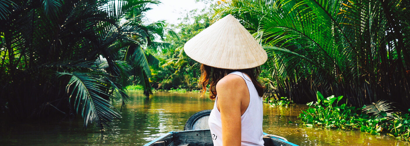 A young woman in a Vietnamese hat rides a boat on the Mekong River in Vietnam.The girl is traveling in a boat along the Mekong Delta in Vietnam.A serene river tour on the Mekong Delta, Can Tho Vietnam