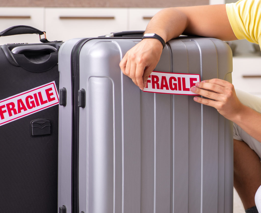 Man placing "Fragile" stickers on his suitcases
